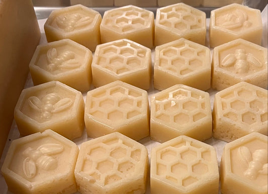 Hexagonal and round soap bars with embossed designs on a white surface