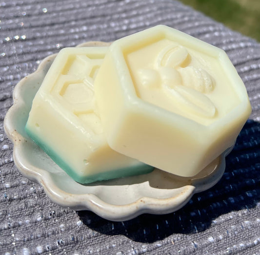 Two hexagonal soap bars with a design on a textured surface