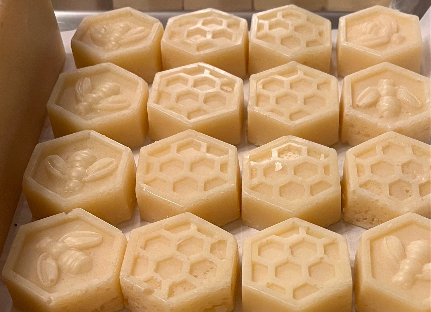Hexagonal and round soap bars with embossed designs on a white surface