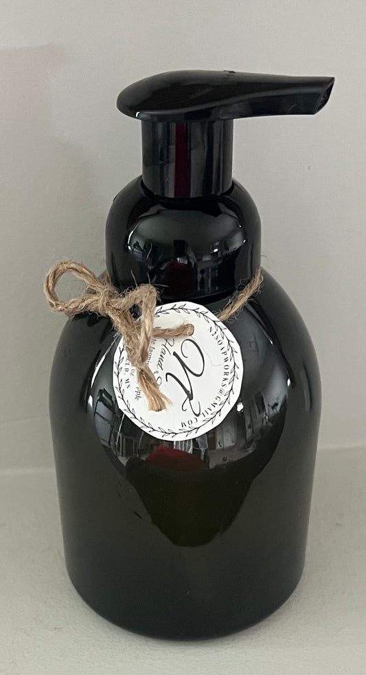Black soap dispenser with a label and string on a light gray background